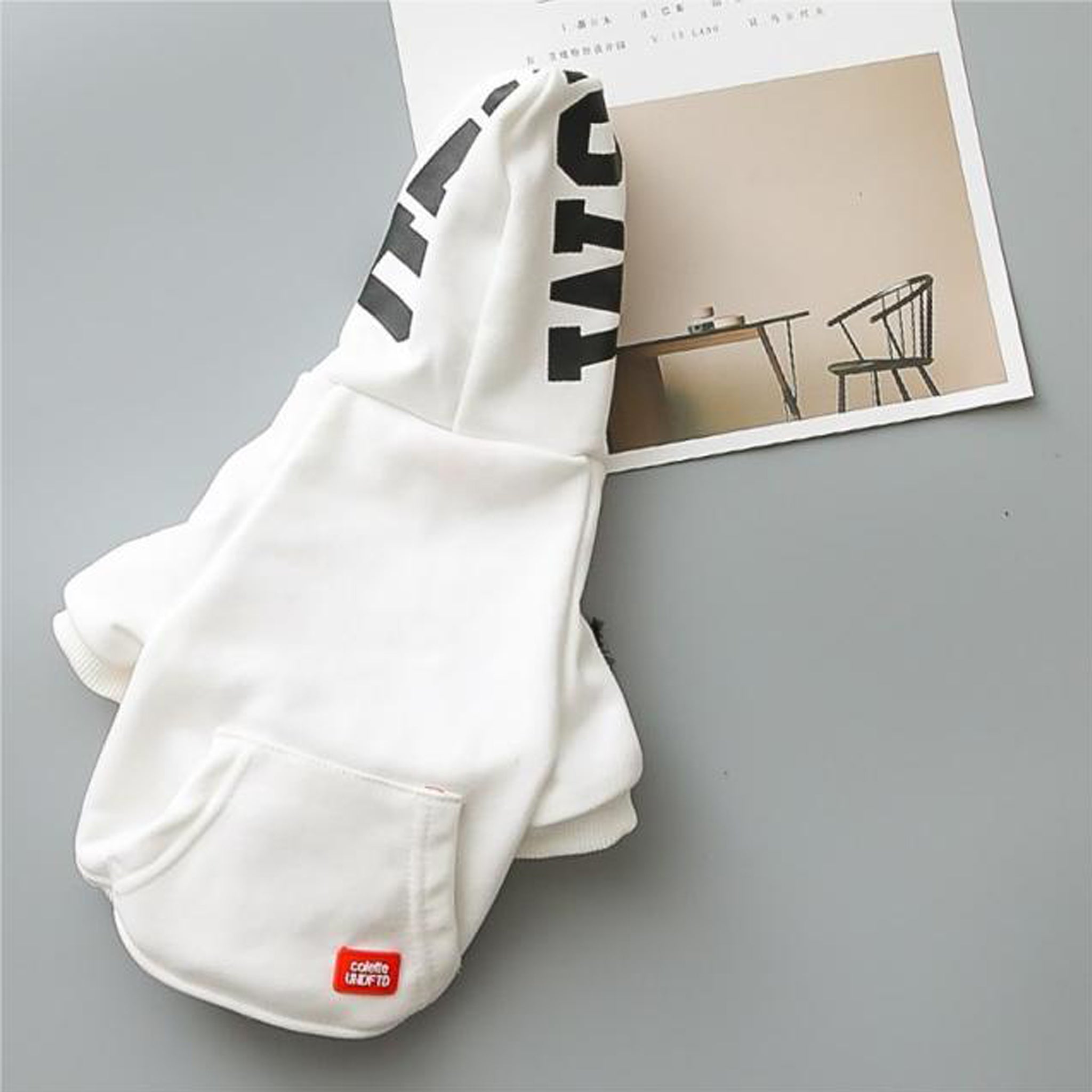 Pasji pulover s kapuco in žepom v beli barvi.